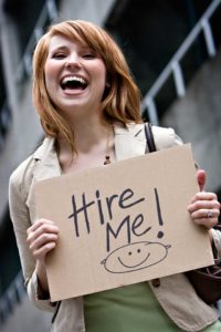 Photo of lady holding a 'Hire Me!' sign.